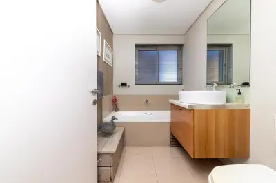 a bathroom with a sink and a tub and a toilet at Beachfront Bliss with Table Mountain Views Horizon Bay 801 in Cape Town