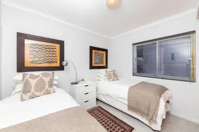a bedroom with two beds and a window at Beachfront Bliss with Table Mountain Views Horizon Bay 801 in Cape Town