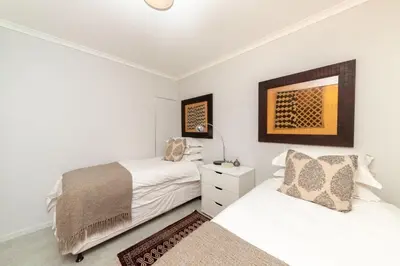 two beds in a bedroom with white walls at Beachfront Bliss with Table Mountain Views Horizon Bay 801 in Cape Town