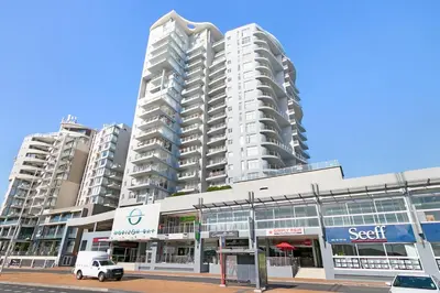 a white car parked in front of a large building at Beachfront Bliss with Table Mountain Views Horizon Bay 801 in Cape Town