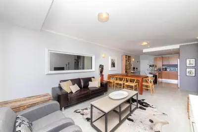 a living room with a couch and a table at Beachfront Bliss with Table Mountain Views Horizon Bay 801 in Cape Town