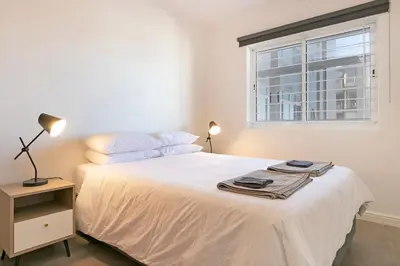a bedroom with a white bed with a window at Chic Beachfront Apt with Table Mountain Views Horizon Bay 902 in Cape Town