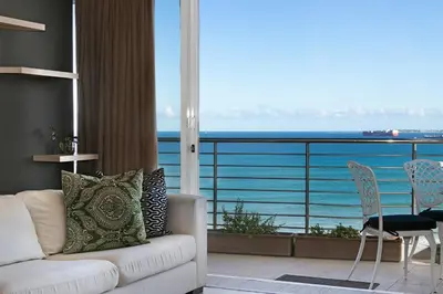 a living room with a couch and a view of the ocean at Chic Beachfront Apt with Table Mountain Views Horizon Bay 902 in Cape Town