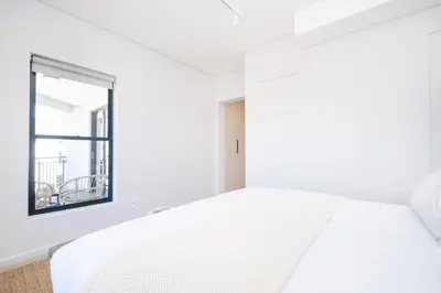 a white bedroom with a bed and a window at 221 Paarl Lux 1 Bdrm Apt with Mountain Views in Paarl