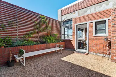 a brick building with a bench next to a window at Trendy Salt River Loft Apartment in Cape Town