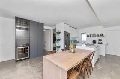 a large white kitchen with a wooden table and chairs at Modern Sea View Retreat with Pool & Inverter Horizon Bay 1405 in Cape Town