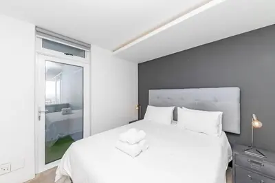 a bedroom with a large white bed with a window at Modern Sea View Retreat with Pool & Inverter Horizon Bay 1405 in Cape Town