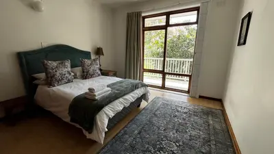 a bedroom with a bed and a large window at Homey Central Apartment By ARPA in Stellenbosch