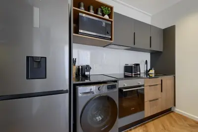 a kitchen with a washing machine and a washer at Luxe On Park Century City in Cape Town
