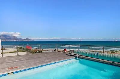 a swimming pool with a boardwalk and the beach at Horizon Bay 1602 Penthouse APT with lovely views in Cape Town