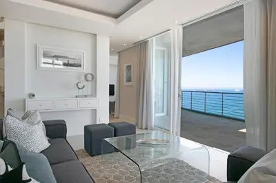 a living room with a glass table and a view of the ocean at Horizon Bay 1602 Penthouse APT with lovely views in Cape Town