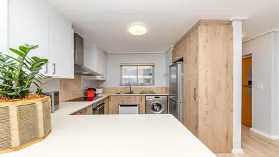 a kitchen with wooden cabinets and a counter top at Lagoon Beach Gem 127 Pool, Views & Sea Breeze in Cape Town