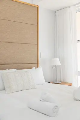 a white bed with a white headboard and a lamp at Lagoon Beach Gem 127 Pool, Views & Sea Breeze in Cape Town