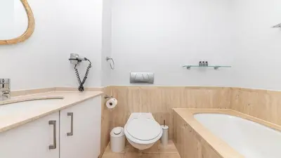 a bathroom with a tub and a toilet and a sink at Lagoon Beach Gem 127 Pool, Views & Sea Breeze in Cape Town