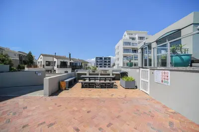 a patio with tables and benches on a building at Seaside Living on Kite Beach, Blouberg Sea Spray A204 in Cape Town