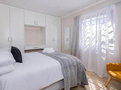 a white bedroom with a bed and a window at Urban Oaks in Bellville