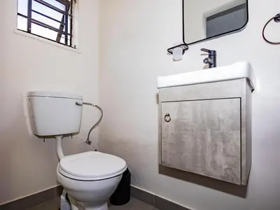 a bathroom with a toilet and a sink and a mirror at Urban Oaks in Bellville
