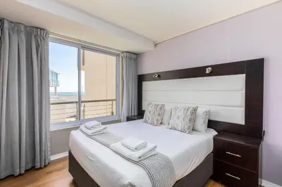a bedroom with a large bed with a large window at Lagoon Beach 124A by CTHA in Cape Town