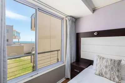 a bedroom with a bed and a large window at Lagoon Beach 124A by CTHA in Cape Town