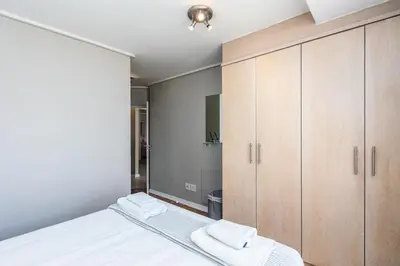 a bedroom with a bed and wooden cabinets at Lagoon Beach 124A by CTHA in Cape Town