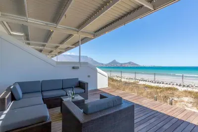 a living room with a couch and a view of the beach at Spinnakers 9 by HMH in Cape Town