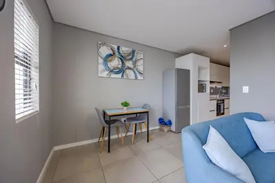 a living room with a blue couch and a table at Beach Break Bliss - Cozy retreat with mountain views in Bloubergstrand