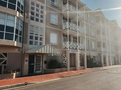 an apartment building with a sign for a music museum at Cozy one bed, just a short walk to the beach in Strand