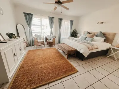 a bedroom with a large bed with a ceiling fan at Cozy one bed, just a short walk to the beach in Strand