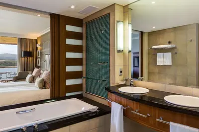 a bathroom with two sinks and a bed and a tub at Arabella Hotel, Golf and Spa in Kleinmond