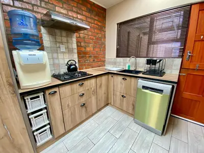 a kitchen with wooden cabinets and a brick wall at Modern Van Riebeeck Park Accomodation in Worcester