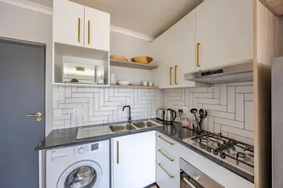 a white kitchen with a sink and a washer at Contemporary Modern 1 Bedroom-19B, Blouberg in Cape Town