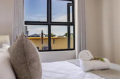a bedroom with a window and a bed with a towel at Contemporary Modern 1 Bedroom-19B, Blouberg in Cape Town