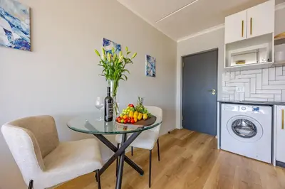 a room with a table with a bowl of fruit on it at Contemporary Modern 1 Bedroom-19B, Blouberg in Cape Town