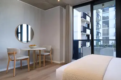 a bedroom with a bed and a table and a mirror at Riverlands Luxury Apartments by City Club in Cape Town