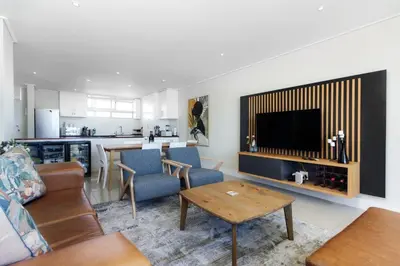 a living room with a couch and a tv and a table at Ashley On Beach 1104 Prestige Style in Strand