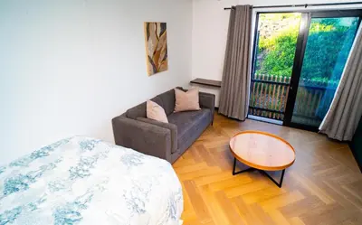 a living room with a couch and a table at Modern Studio Steps from Ratanga Park in Cape Town