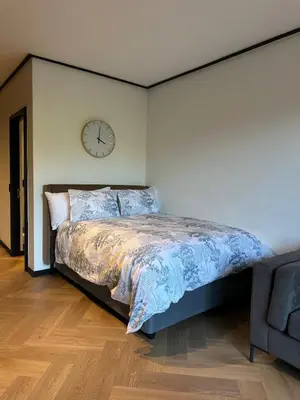 a bedroom with a bed and a clock on the wall at Modern Studio Steps from Ratanga Park in Cape Town