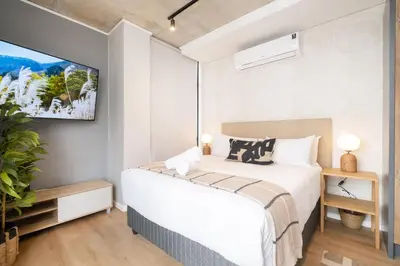 a bedroom with a bed and a tv on the wall at S500 Riverlands - Lux Studio Apartment in Cape Town