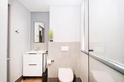 a white bathroom with a toilet and a mirror at S500 Riverlands - Lux Studio Apartment in Cape Town
