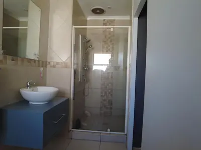 a bathroom with a shower with a sink and a mirror at Studio Flat Bayside in Cape Town
