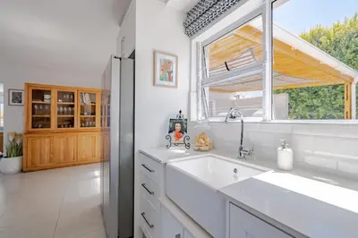 a white kitchen with a sink and a window at Serenity on 6th Luxury holiday home in Hermanus