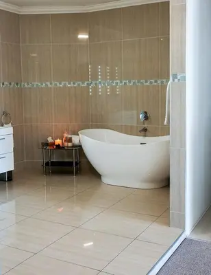 a bathroom with a large tub and a tile floor at Misty Waves Boutique Hotel in Hermanus