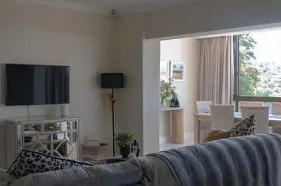 a living room with a couch and a television at Begonias Eden in Helderberg