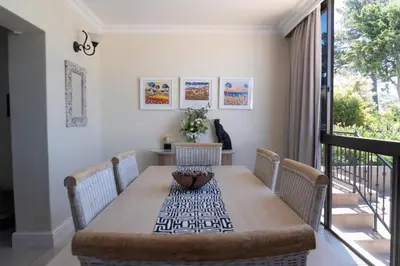 a dining room with a wooden table and chairs at Begonias Eden in Helderberg