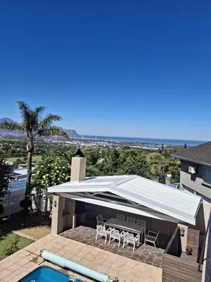 a patio with a white roof and a table and chairs at Begonias Eden in Helderberg