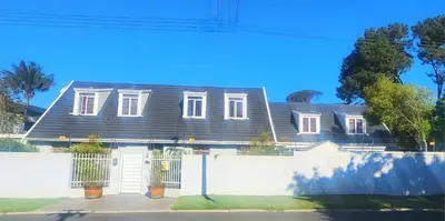 a house with a black roof and a white fence at Tranquil Holiday Home with Pool & Garden 4 bedrooms in Cape Town