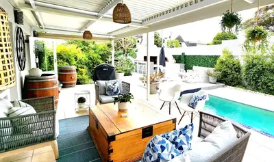 an outdoor patio with a table and a pool at Tranquil Holiday Home with Pool & Garden 4 bedrooms in Cape Town