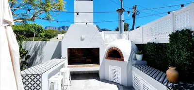 a white house with a fireplace on a patio at Tranquil Holiday Home with Pool & Garden 4 bedrooms in Cape Town
