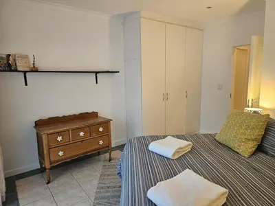 a bedroom with a bed and a dresser with two towels at Fair View 2 in Somerset West