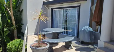 a patio with a table and two benches next to a door at Fair View 2 in Somerset West